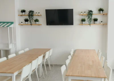 Zona de comedor con televisión y estanterías decorativas en local de eventos Sala Macanaz.
