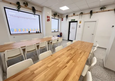 Comedor con mesas largas de madera y sillas blancas en la Sala Macanaz, Zaragoza.
